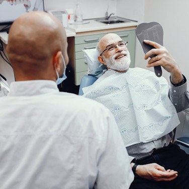 dental patient admiring his new smile in a mirror 