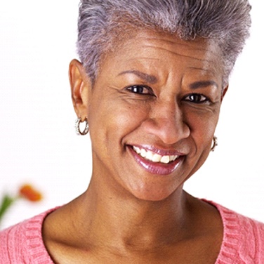 Older woman with pink shirt and earrings smiling
