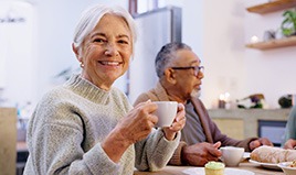 Woman smiling while enjoying breakfast with friends in kitchen