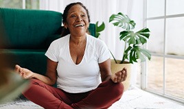 Senior woman smiling while meditating at home