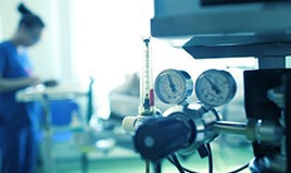 Medical machine in foreground with medical professional in scrubs blurry in background