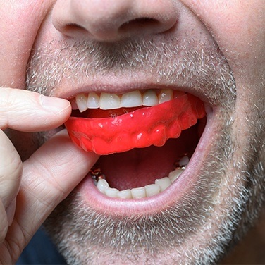 man putting in red mouthguard