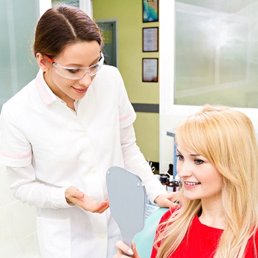 A woman smiling in the mirror at the dentist’s office