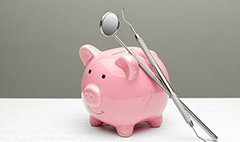 dental instruments resting on a pink piggy bank 