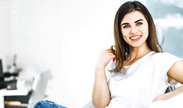 Woman in jeans smiling while sitting in dental chair