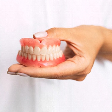 Dentist holding full dentures in Wilton Manors