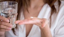 Woman with a glass of water and pill in her hand