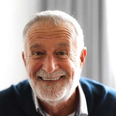 Senior man wearing blue shirt at home smiling