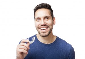 Smiling man holding Invisalign tray