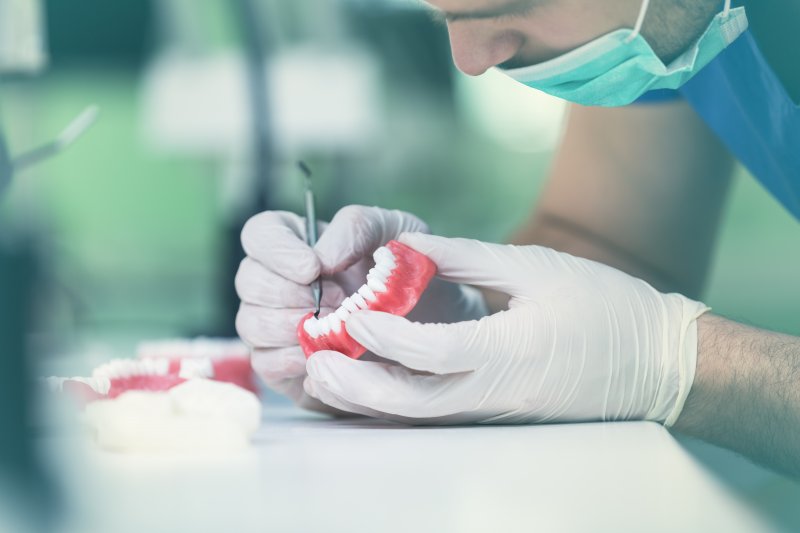 A prosthodontist working on a bottom arch model.