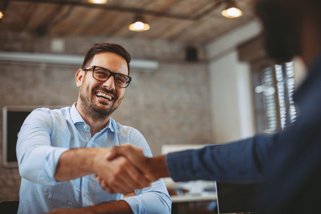 Man smiling while shaking a colleague’s hand