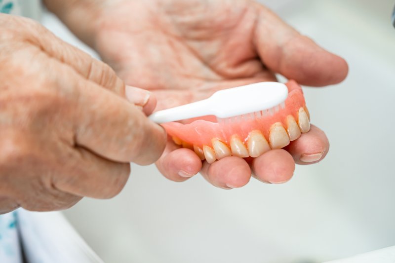 person brushing dentures in Wilton Manors